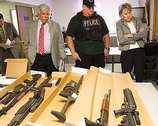Paul Gains, left, Mahoning County prosecutor, Officer Don Cox from YSU police, and Judge Theresa Dellick of the
county’s juvenile court look over some of the weapons seized when gang suspects were arrested Tuesday.