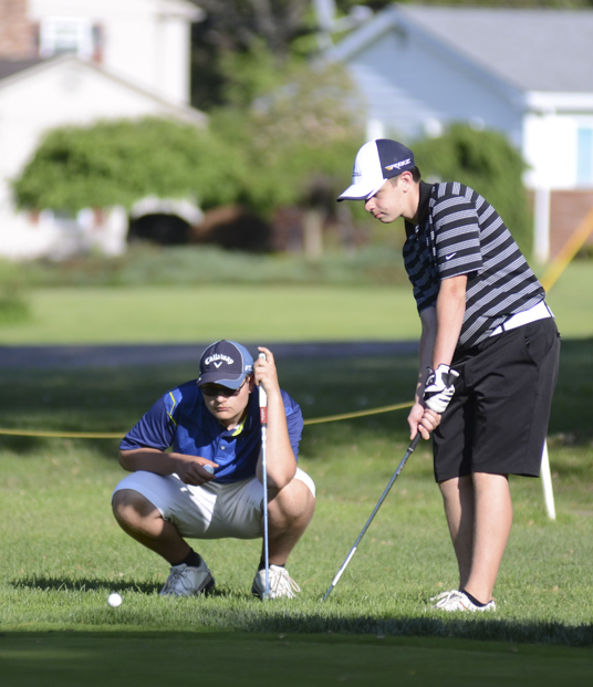 Katie Rickman | The Vindicator.Vince Goleno, 17, of Austintown (left) watches as Alec Hamilton, 15, also of Austintown putts during the Greatest Golfer Junior Qualifiers May 24, 2014.