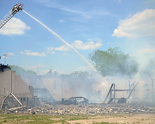 Jake Zimmerman, a firefighter with the Western Reserve Joint Fire District in Poland, hoses down the remains of a Struthers building at 625 Spring St. that caught fire Monday morning.