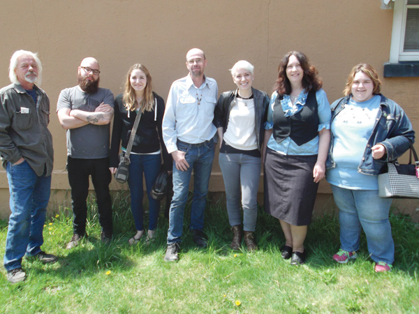 Posing for a photograph in front of the blank wall that will soon be covered with a mural depicting life throughout the decades in the Youngstown Sheet & Tube Co. worker housing complex in Campbell are, from left, David Donofrio, Clayton Donofrio, Marcy Gussenhofen , Tim Sokoloff , Katelyn Gould, Linda Gens and April Caruso-Richards. Gould, a Pittsburgh-based artist, will paint the mural, and be assisted by Gussenhofen. Sokoloff , Gens and Caruso-Richards are the Iron Soup Historical Preservation Co.’s president and chairman, executive director and board secretary, respectively.