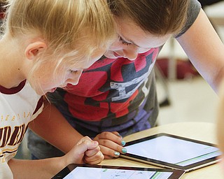 Fifth-graders Harley Novak, left, and Jillian Strecansky of South Range Middle School work on iPads during class. They use the devices to work on a math program that walks them through a tutorial to show them how to fix a problem they got wrong.