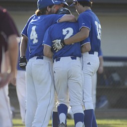 Katie Rickman | The Vindicator.Poland's Nick Maillis (no. 4 on left) and Jon Shurilla  (no. 15 on right) and another team mate hug Chase Knodle who batted last and was called out at first base causing Poland to lose to Woodridge 3-2 in the 7th inning.