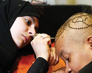 Lamia Alfares, a local Henna artist, draws a Henna crown on the head of Monaca Beasley-Martin at the Calvin
Center in Youngstown. Beasley-Martin has alopecia, a condition in which a person is allergic to his or her own hair and becomes bald.