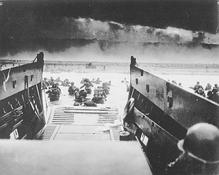In this image provided by the U.S. Coast Guard, while under attack of heavy machine gun fire from the German coastal defense forces, these American soldiers wade ashore off the ramp of a U.S. Coast Guard landing craft, during the Allied landing operations at Normandy, France on June 6, 1944. (AP Photo/U.S. Coast Guard)