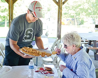 Austin Yemma, a senior at Struthers High, serves cookies to Marinell Szalaj of Struthers during the event. Yemma and other members of the school’s boys basketball team were among those who volunteered to help out at the event.