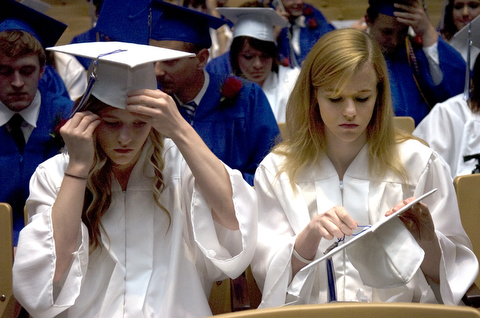 Kelli Cardinal/The Vindicator.Graduate Kayle Augustine, right, fixes the tassel on her cap Sunday next to her twin sister Jessica before walking into the fieldhouse for commencement at Poland Seminary High School.