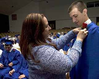 Kelli Cardinal/The Vindicator.Graduate Ryan Burkert receives his red rose boutonniere Sunday from Julie Walsh, a family and consumer science teacher, before walking into the fieldhouse for commencement at Poland Seminary High School.