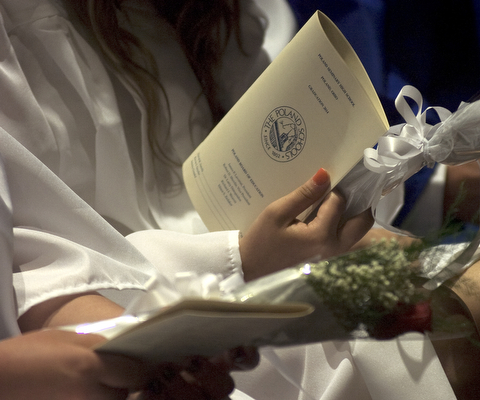 Kelli Cardinal/The Vindicator.A graduate holds her program and a single red rose Sunday before walking into the fieldhouse for commencement at Poland Seminary High School.