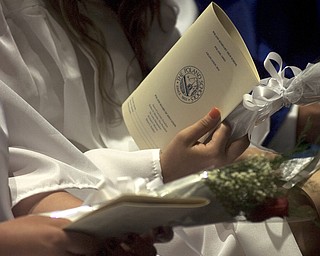Kelli Cardinal/The Vindicator.A graduate holds her program and a single red rose Sunday before walking into the fieldhouse for commencement at Poland Seminary High School.