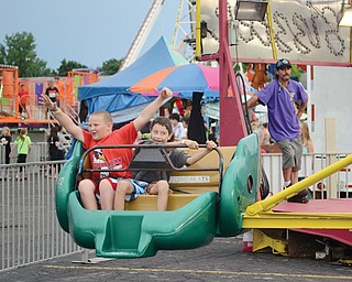 At left, Mark Cole throws his hands in the air, as Cody Rivera attempts to defy gravity while on a ride at the 41st annual St. Nicholas Church Festival on Wednesday evening. The two 10-year-olds, both of Youngstown, were among those who came out for the festival’s opening day, despite the threat of rain.