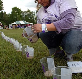 Kelli Cardinal/The Vindicator.Pam Jones, of North Lima, places names on the luminarias Friday during the 2014 Austintown Relay For Life event in Austintown Township Park. The names are in honor or memory of those who have battled cancer.