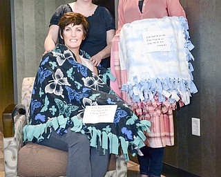 Sherrie Campana of Boardman, seated, is wrapped in a Blanket of Hope made by Emily Erb of Green Township, right, as her senior project at South Range High School. Emily was inspired to help cancer patients when Campana, a friend of her mother, Mary Kay Erb, left, was diagnosed with breast cancer.