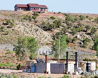 In this June 9 photo, an oil-and-gas well pad and storage tanks sit below a home in a sparsely populated area near New Castle, Colo., a small farming and ranching settlement on the Western Slope of the Rockies. Four in 10 new oil and gas wells near national forests and fragile watersheds or otherwise identified as higher pollution
risks escape federal inspection, according to an Associated Press review that shows wide state-by-state disparities in safety checks.