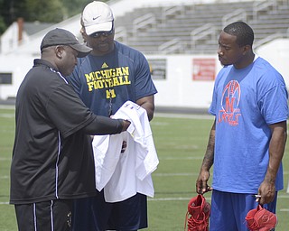 Katie Rickman | The Vindicator.Coaches Alan Caldwell (left) and Dave Arnold speak with Mario Manningham on the field at Warren G. Harding High School June 21, 2014.