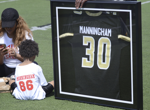 Katie Rickman | The Vindicator.Mario Manningham Jr. (left) sits next to his father's retired jersey at Warren G. Harding High School June 21, 2014. Mario Manningham's fiance Tiffany Hughley sits to the left of her son.