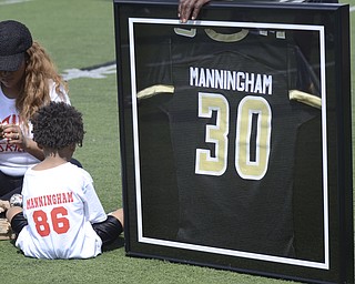 Katie Rickman | The Vindicator.Mario Manningham Jr. (left) sits next to his father's retired jersey at Warren G. Harding High School June 21, 2014. Mario Manningham's fiance Tiffany Hughley sits to the left of her son.
