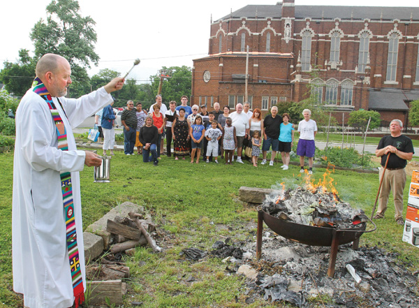 The Rev. Ed Noga, pastor of St. Patrick Church, 1420 Oak Hill Ave., Youngstown, blesses the bonfire that is being used to burn “torn and worn” religious articles. The occasion Monday was the vigil of the Feast Day of St. John the Baptist.