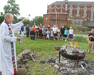 The Rev. Ed Noga, pastor of St. Patrick Church, 1420 Oak Hill Ave., Youngstown, blesses the bonfire that is being used to burn “torn and worn” religious articles. The occasion Monday was the vigil of the Feast Day of St. John the Baptist.