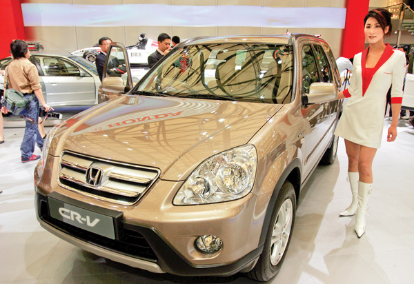 A model poses by a Honda CR-V at Auto Shanghai 2005 exhibition in Shanghai, China. Honda, Mazda and Nissan are recalling millions of vehicles globally for defective airbags manufactured by supplier Takata Corp. that could possibly explode.