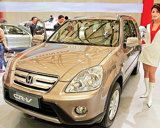 A model poses by a Honda CR-V at Auto Shanghai 2005 exhibition in Shanghai, China. Honda, Mazda and Nissan are recalling millions of vehicles globally for defective airbags manufactured by supplier Takata Corp. that could possibly explode.