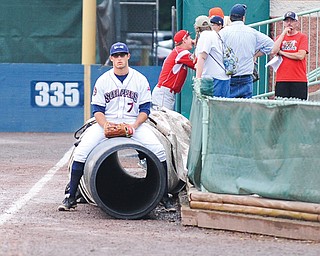 Scrappers outfielder Josh McAdams sits on the tarp during a rain delay prior to Tuesday night’s game against the Batavia Muckdogs at Eastwood Field in Niles. Stormed continued to roll through the region, postponing the game until today when the teams will play a doubleheader. Game 1 will be at 5 p.m.