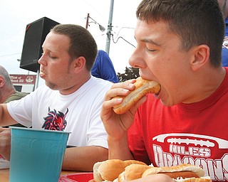 Ryan Ford, a Niles High School football player, right, chows down on a hot dog during an eating contest at Harry Stevens Hot Dog Day on Sunday. At left is Niles football coach Luke Stucke.