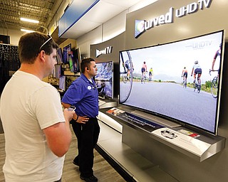 Jake Willis, center, home-theater supervisor at the Best Buy store in Greenwood, Ind., talks with customer Landon
Leichter, of Spencer, Ind., at a display featuring a Samsung 78-inch curved television at the store in Greenwood, Ind. The 78-inch television is flanked by 65-inch versions. Americans increasingly are replacing their once-enviable 50-inch TVs with even bigger screens.