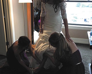 Lisa Plummer of Columbus, right, lifts up the dress while Rachel Nock of Canfield, left, helps her big sister Bridget Boysen of Seattle, slip into her wedding shoes. The wedding took place Sept. 14, 2013, in Seattle. Sent by Anne Nock of Canfield.