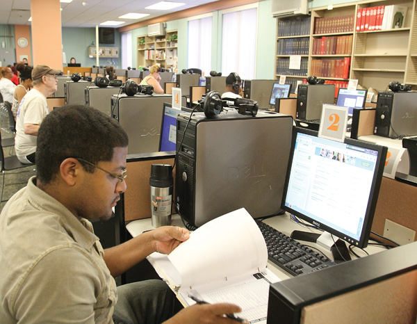 Alex Armstrong of Warren combines paperwork and online research at the Warren-Trumbull County Public Library’s Adult Computer Area. The computer lab reopened in mid-June after a monthlong renovation project that cost about $20,000 and was paid for out of the library’s general fund. Below, Taylor Wade of Warren is among the patrons of the library’s newly remodeled Adult Computer Area. The lab is one of three in the main branch that serves an average of 3,000 people per month.