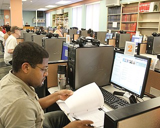 Alex Armstrong of Warren combines paperwork and online research at the Warren-Trumbull County Public Library’s Adult Computer Area. The computer lab reopened in mid-June after a monthlong renovation project that cost about $20,000 and was paid for out of the library’s general fund. Below, Taylor Wade of Warren is among the patrons of the library’s newly remodeled Adult Computer Area. The lab is one of three in the main branch that serves an average of 3,000 people per month.