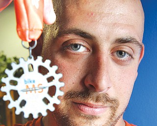 Shawn Tiberio of Boardman has his game face on as he looks forward to participating Aug. 2-3 in the 2014 MS Pedal to the Point Ride to raise money and awareness for multiple sclerosis. He is holding the medal he received
for participating in the 2013 ride.