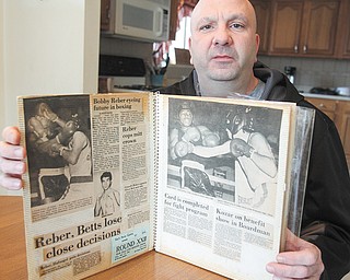 Reber holds a scrapbook of clippings from his boxing days. He now suffers from dementia, which he says is a result of injuries suffered while boxing.