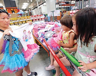 Carry Johnson, left, shows dresses to her daughters Zoey, center, and Payton while they shop at a Costco in Plano,
Texas. The private Conference Board reported Tuesday that consumers are more confident about the economy
than they have been in nearly seven years.