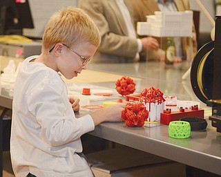 Ryder Fielding, 8, of Dayton plays with one of several items made using 3-D printing Thursday at the America Makes facility on Boardman Street in downtown Youngstown.