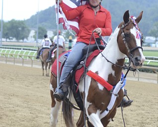 Katie Rickman | The Vindicator.An outrider pony walks the track with a rider displaying the flag prior to the start of the West Virginia Derby August 2, 2014.