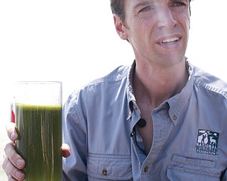 Collin O’Mara, president and CEO of the National Wildlife Federation, holds a sample glass of water as he talks about algae near the city of Toledo water intake crib Sunday in Lake Erie.