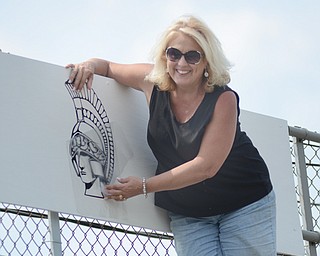 Carie Croutch of Boardman applies a Spartan decal to the back wall of the stands at Boardman’s football stadium during a scheduled cleanup day recently where students and community members gathered to get the stadium ready for the upcoming season. The turf section of the new stadium project is set to be finished by Labor Day.
