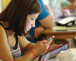 Allison Morgan, an eighth-grade science teacher in the Boardman School District, uses interactive media devices — a smartphone and iPad — during the first day of a technology conference at Boardman High School.