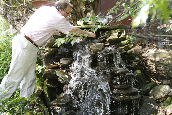       ROBERT K. YOSAY  | THE VINDICATOR.. Pastor Dave adjusts the rocks on his waterfall at the Our Lady of the Lakes Parish-- has an oasis for solitude or just reflection or just enjoying the flowers as the Rev. David W. Merweiler is pastor and gardener.....  -30-
