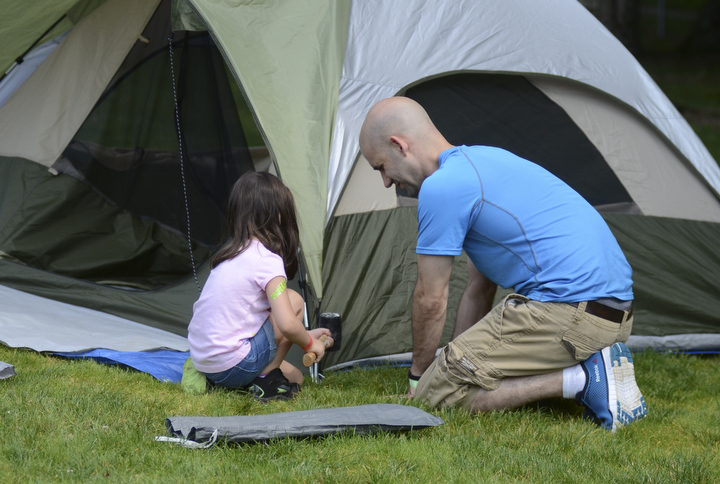 Katie Rickman | The V indicator.Peyton Arn, 4 of Boardman helps her father Ben Arn put their tent up at Family Camp at Mill Creek MetroPark August 9, 2014.