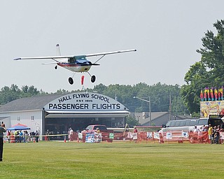 Jeff Lange | The Vindicator Spectators watch and take pictures as a plane flies by during the Wings and Wheels event held on Saturday at the Ernie Hall Aviation Museum in Warren.