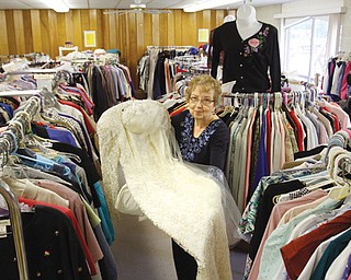 JoAnn Truax, coordinator of Helping Hands Closet at Western Reserve United Methodist Church in Canfield, shows a beaded wedding gown that’s available. Racks and turnstiles at the closet are filled with new and gently worn merchandise that is sold for reasonable prices. Money benefits charitable projects of the church.