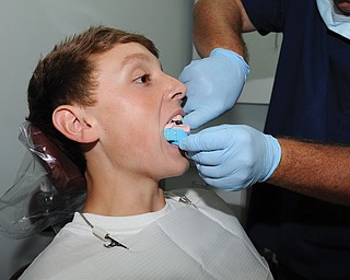 Dr. Andrew Patton makes a dental impression of East Palestine High School football player Seth Dowd’s mouth
Wednesday at his office in East Palestine. Every member of the Bulldog team will have their mouths molded for custom fitted mouthguards which the team will be using in the upcoming football season to help reduce the risk of concussions.