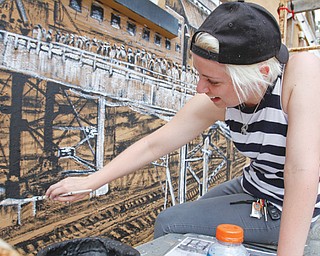 Katelyn Gould, a Pittsburgh-based artist, formerly of Campbell, paints a mural on a bare wall at the former Youngstown Sheet & Tube Co. workers’ housing site in Campbell. Weather permitting, she hopes to have the mural completed Saturday. Gould began painting the mural Aug. 10 thanks to a successful Kickstarter campaign that funded her supplies and travel expenses.