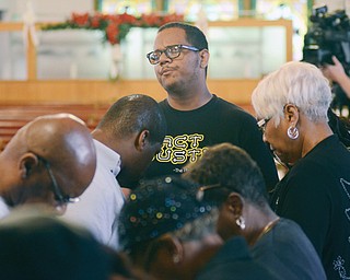 Allan Irizarry-Graves of Youngstown prays with residents at Tabernacle Baptist Church in Youngstown on Wednesday night at a vigil for Ferguson, Mo., which is besieged by civil unrest after a police shooting of a black teen.