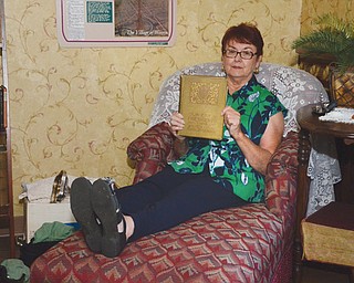 Sandy Sarsany, above, curator of the Upton House, relaxes on a chaise lounge, one of two original pieces to the home where suffragist Harriet Taylor Upton lived for nearly 60 years. Sarsany holds the book, “Our Early Presidents, Their Wives and Children,” which was written by Upton.