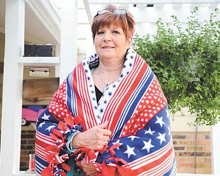 Katie Rickman | The Vindicator — Carol Landis wraps a homemade blanket around herself that she and a small group of volunteers of Operation Wrapped in Love made. The group sells blankets and with each sale donates one to a veteran.