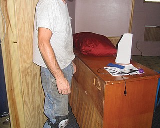 Ray Clendenin stands next to a dresser in the basement of his father-in-law’s home in Girard on Thursday. The warped part of the dresser shows how high the water rose in the basement of the home early Tuesday — about 2 feet.