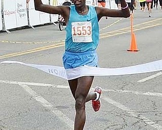 Abraham Chelolnga breaks the tape as he crosses the finish line to win the Panerathon 10 K race Sunday in Youngstown. Panerathon has now raised $1 million to fi ght breast cancer.