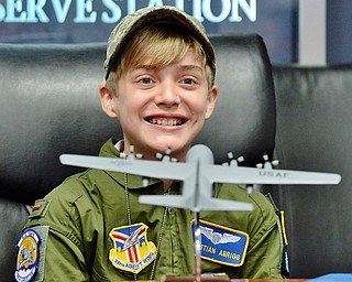 13 year old Christian Abrigg smiles behind his model plane as he watches the military video provided by the Pilot for a Day program at the 910th Airlift Wing, Wednesday morning. Christian is the son of Jody and Byron Abrigg.